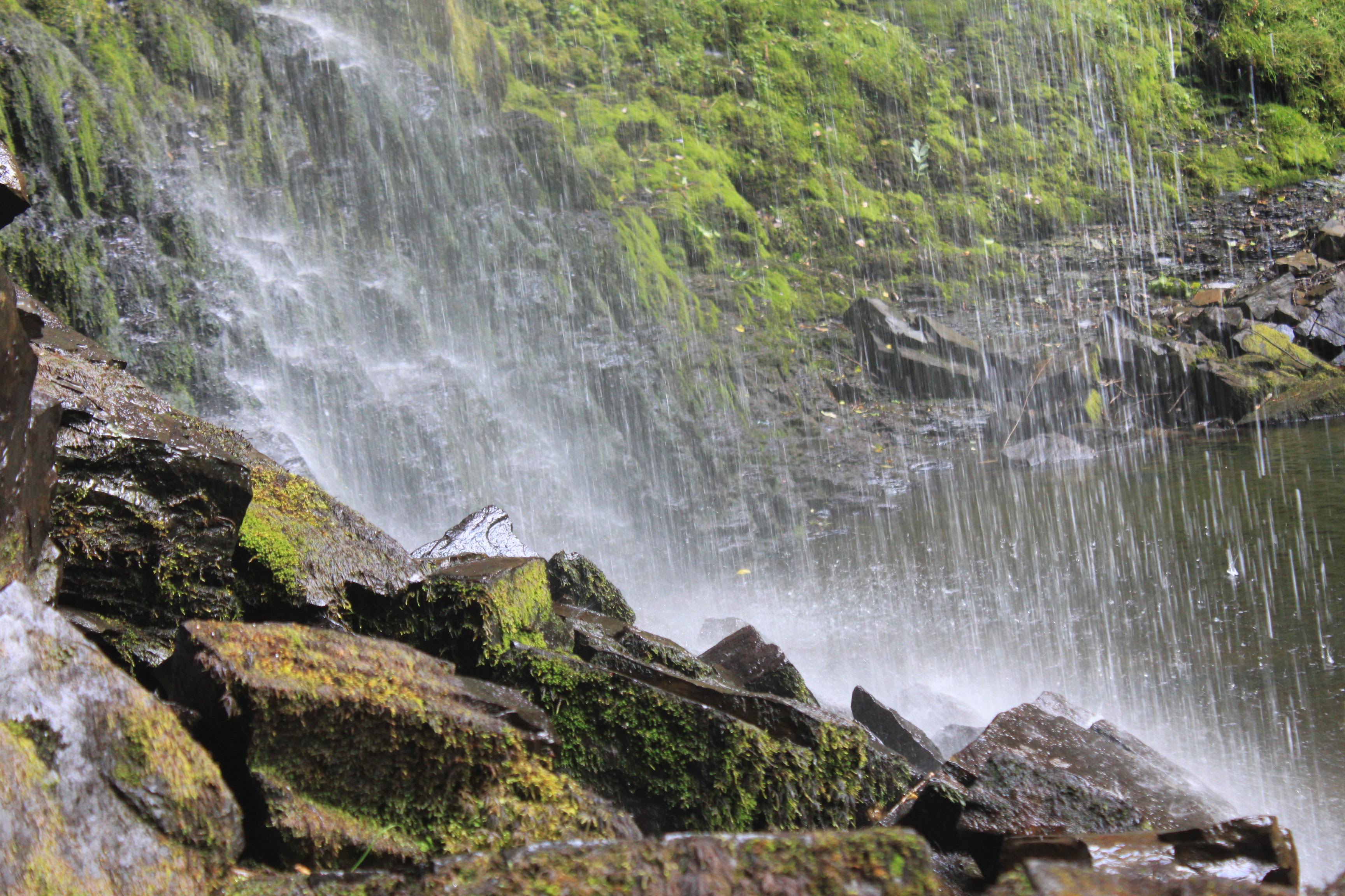 a shot from behind a waterfall with wet rocks.