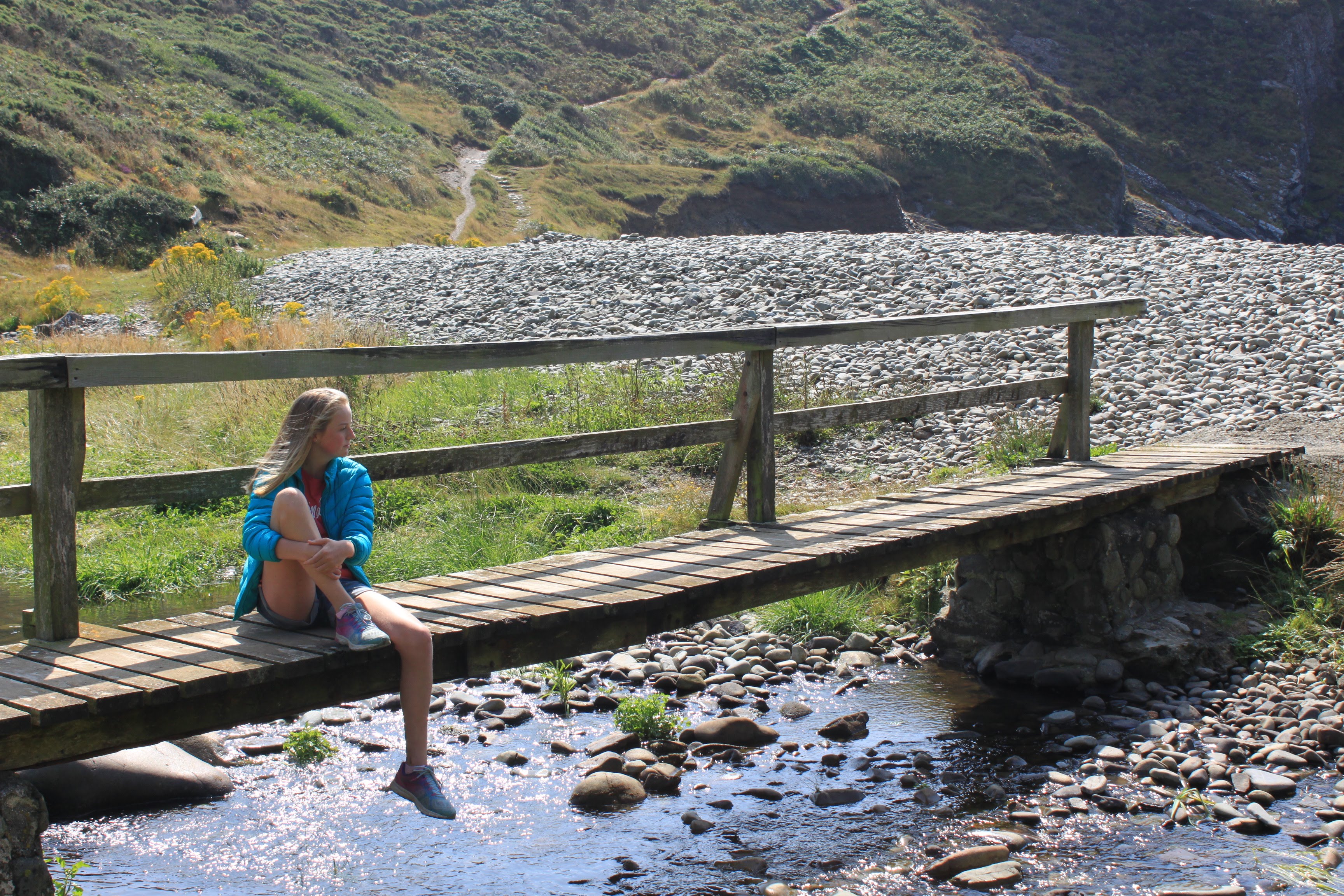 an image of a young female sat on a bridge.