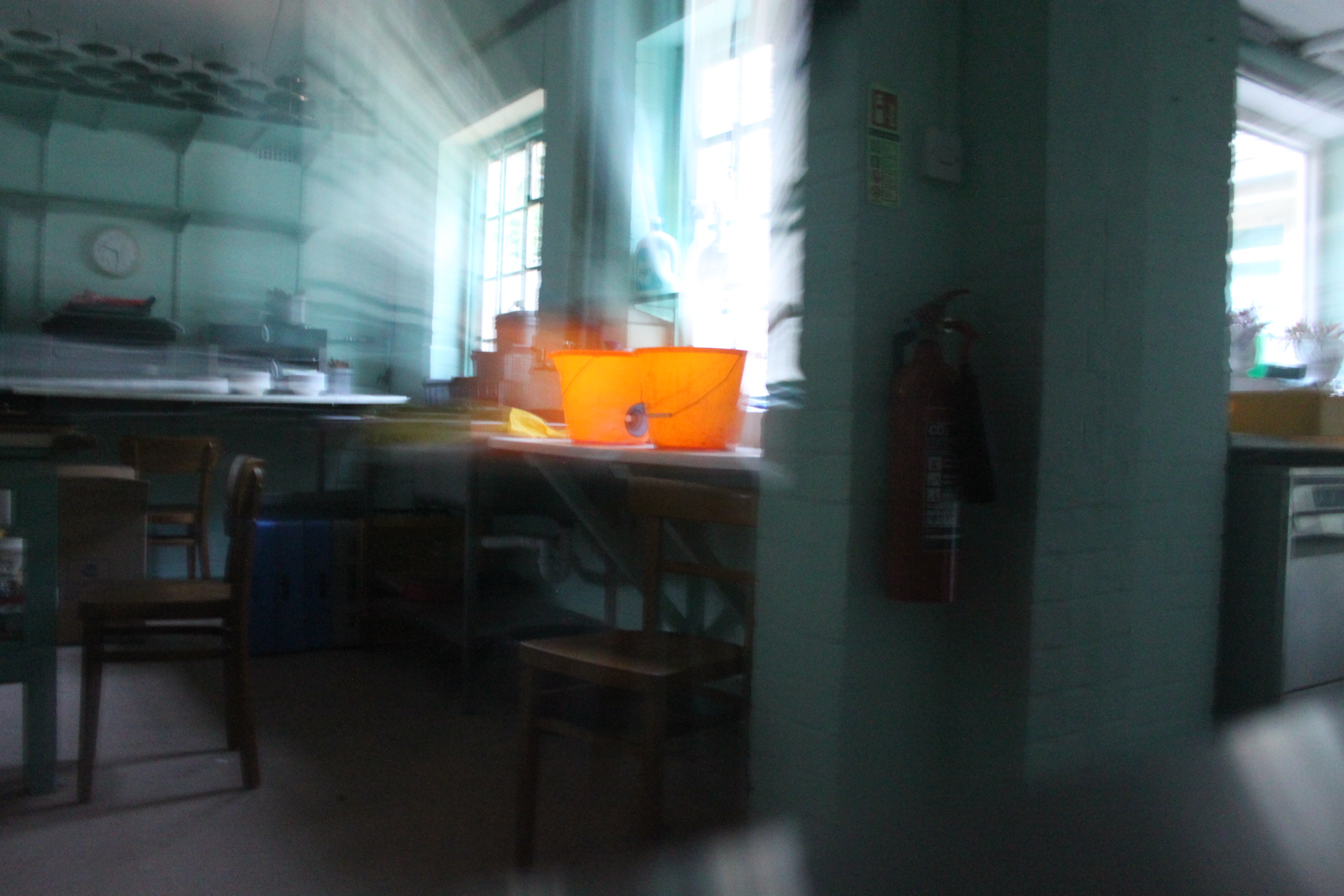 a blurry image of two orange buckets sitting on a work surface with light streaming through the window behind them.