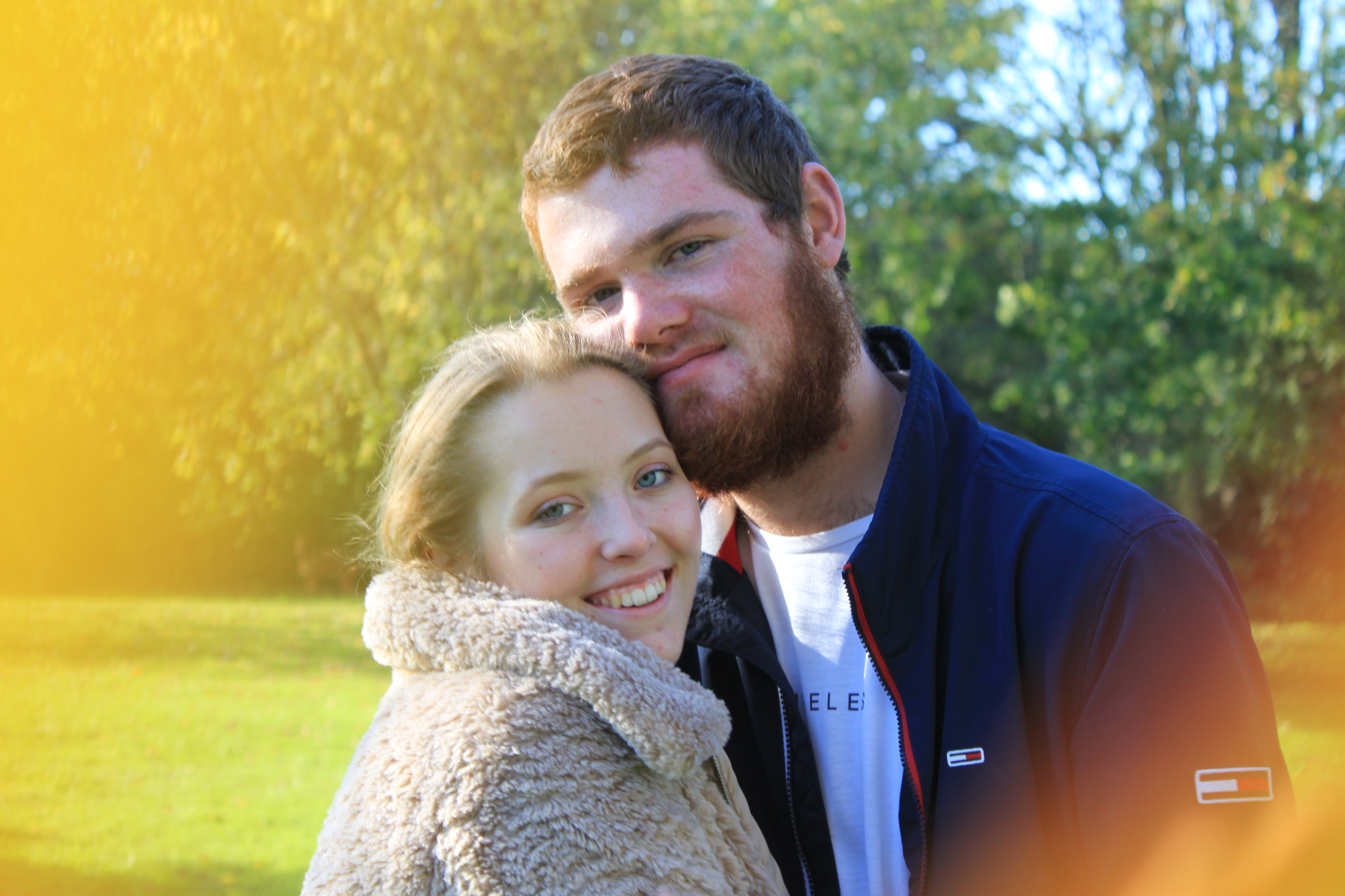 an image of a straight couple who are smiling into the camera with yellow and orange blurs in the corners of the image.