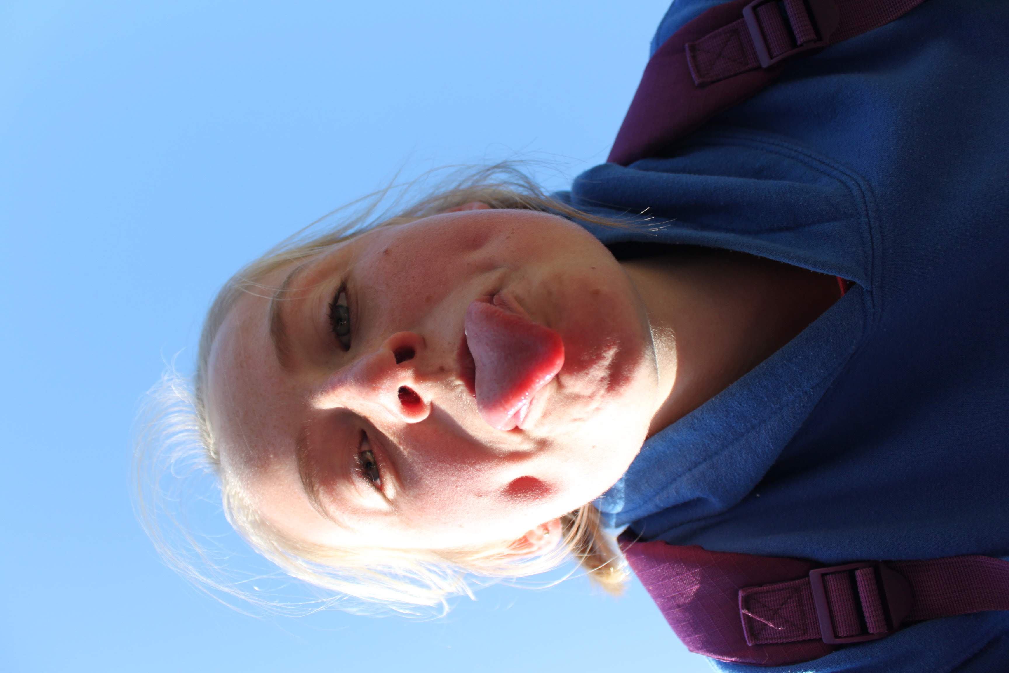 an image of a teenage girl with her tounge out standing over the camera.