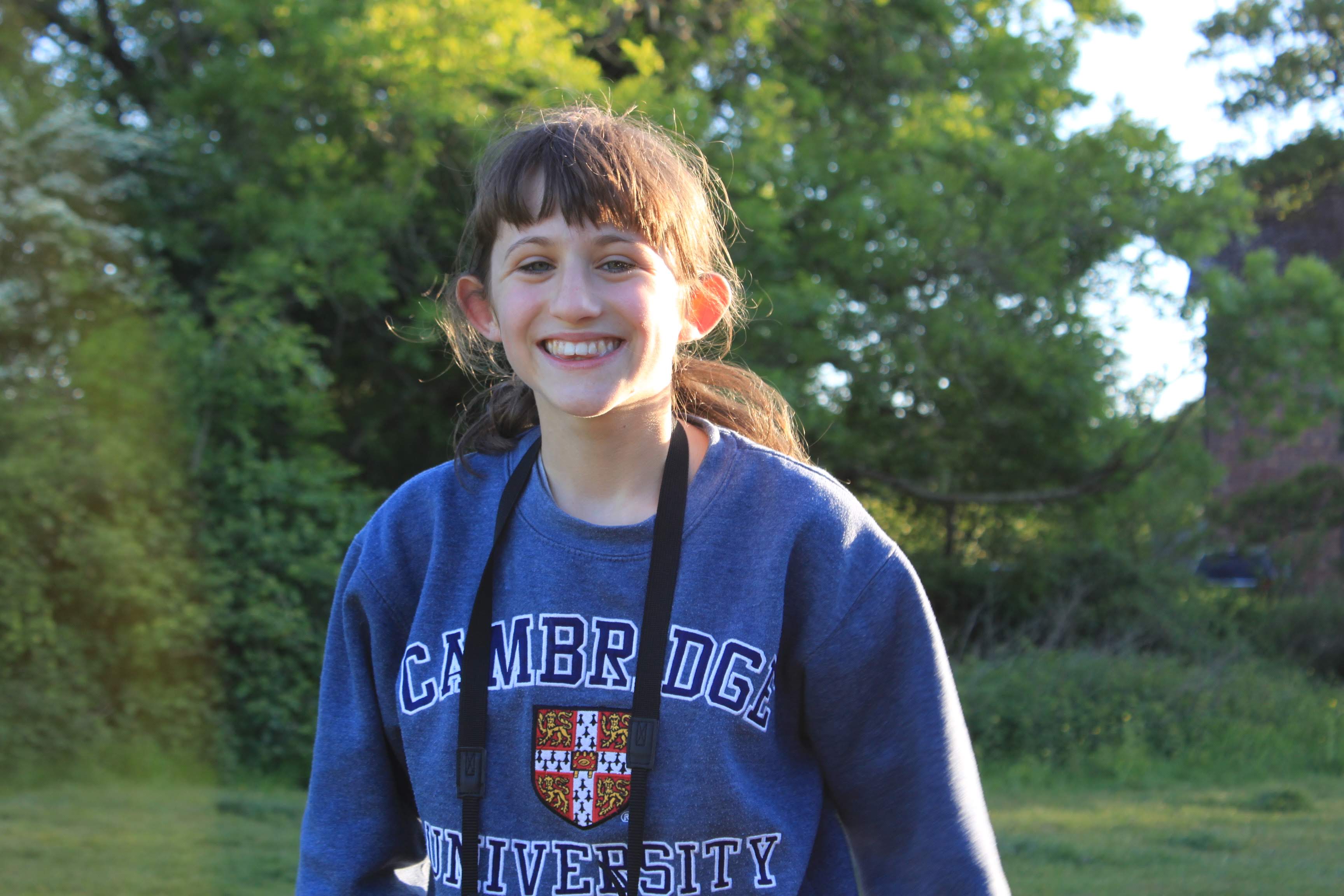 an image of a white female with brown hair who is similing into the camera with trees behind her.