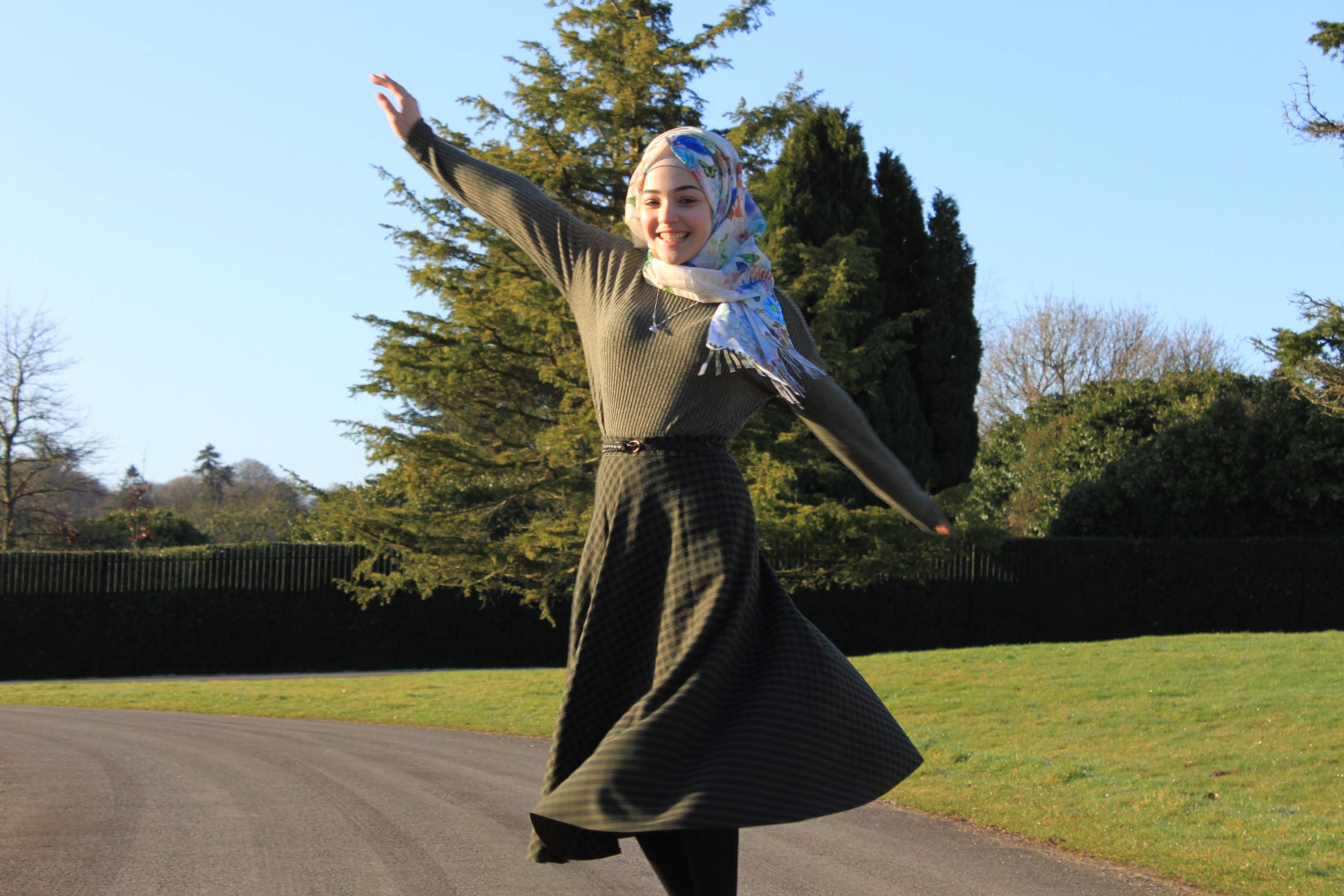 an image of a muslim teenager wearing a hijab who is smiling and spinning round.