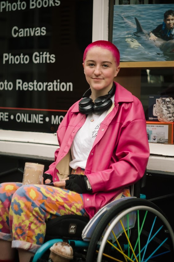 A picture of Juliette, a white fem person in a wetsuit who is smiling into the camera.